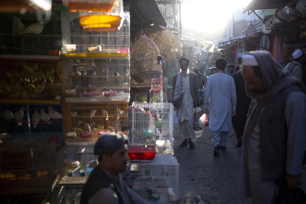 Fichier - Sur cette photo d'archives du mardi 12 octobre 2021, des Afghans traversent un marché à Kaboul, en Afghanistan. Avec le gel des avoirs afghans aux États-Unis et la réticence du monde à reconnaître les talibans, le système bancaire du pays est à l'arrêt. Les salaires impayés et la crise humanitaire qui se profile accentuent la pression sur le nouveau gouvernement taliban, qui n'a pas de solution claire. (AP Photo/Ahmad Halabisaz, File)